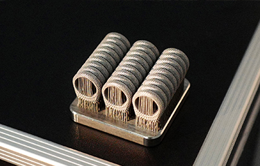 Three cylindrical metal parts with support structures on a build plate